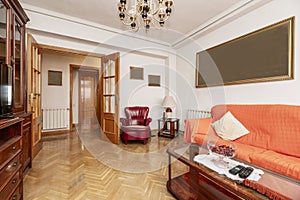 living room with reddish wood table with matching glass bookcase, fabric upholstered sofa and red skai sofa