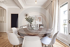 Living room with a round wooden table surrounded by white chairs,