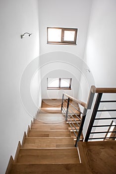 Living room staircase, modern minimalist interior design. Wooden staircase with metallic elements at private mansion