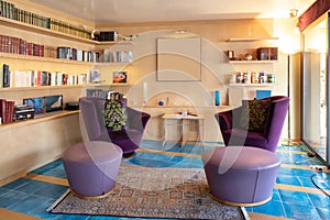 Living room with two large purple armchairs and wooden bookcase