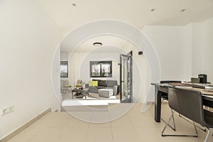 Living room on two levels of a single-family home with smooth white painted walls and metal carpentry of black aluminum and glass