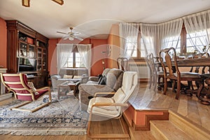 Living room with a two-story floor in a house with wooden furniture, fabric upholstered sofas and many windows