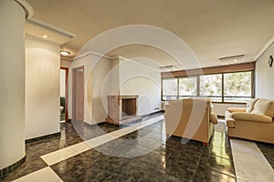 Living room with two-tone stoneware floor, antique furniture, large window, yellow fabric sofa, refractory brick fireplace and