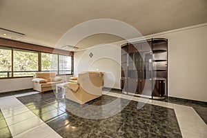 Living room with two-tone stoneware floors, a wall-to-wall window, a fabric lounge set, and old furniture