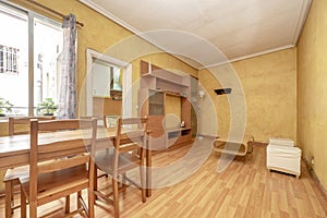 Living room with wooden dining table with matching chairs and wooden flooring and yellow walls