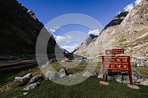 .Llamacorral camp sign next to tents and snowy mountains in the background in the quebrada santa cruz