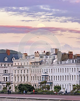 Hotels on Central Promenade St George's Cres in North Wales with the moon rising in a colorful sunset sky