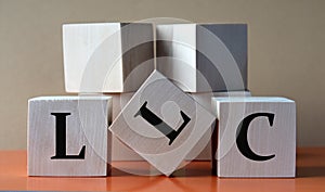 LLC- acronym on large wooden cubes on light brown background