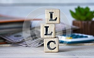 LLC - acronym on wooden cubes on the background of a cactus and banknotes