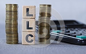 LLC - acronym on wooden cubes on the background of coins and calculator