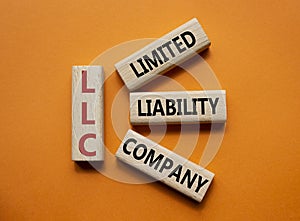 LLC - Limited liability company. Wooden cubes with word LLC. Beautiful orange background. Business and LLC concept. Copy space
