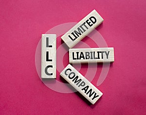 LLC - Limited liability company. Wooden cubes with word LLC. Beautiful red background. Business and LLC concept. Copy space