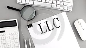 LLC Limited Liability Company written on paper with office tools and keyboard on the grey background