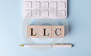 LLC on wooden cubes with pen and calculator, financial concept
