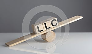 LLC on wooden cubes on a wooden balance , business concept