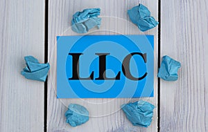 LLC - word on blue paper on a light background with crumpled pieces of paper