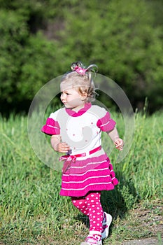 Llittle child girl runs on grass on meadow.