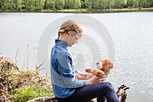 Llittle cute girl play with teddy bear on summer outdoors. Friend Concept