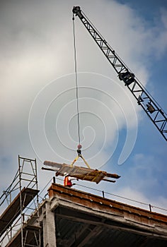 A load on a crane being directed by a construction worker