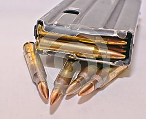 A loaded AR-15 rifle magazine on top of four .223 caliber bullets