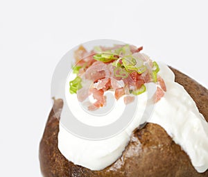 Loaded baked potato on white background with copyspace