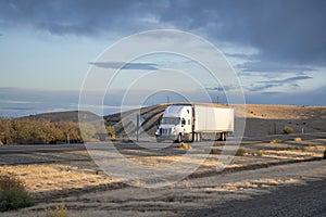 Loaded long haul big rig white semi truck transporting cargo in reefer semi trailer running on the road in sunny time