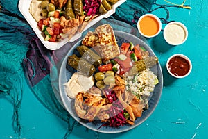 Loaded sharing portion of traditional Mediterranean Arabic food of hummus, olives, grilled chicken, halloumi, dolma, couscous,