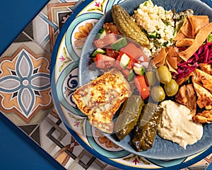 Loaded sharing portion of traditional Mediterranean Arabic food of hummus, olives, grilled chicken, halloumi, dolma, couscous,