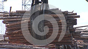 the loader bucket grabs and lifts a pile of firewood, logging and lumber for eco-fuelled boilers.