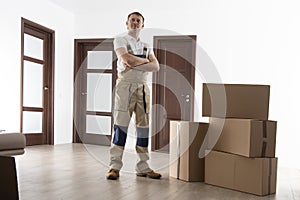 Loader with cardboard boxes in apartment. Mover at house. Relocation services man.