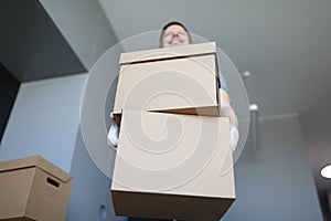 A loader in an empty room holds a cardboard