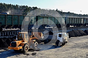 Loader excavator loads coal into a dump truck at a cargo railway station