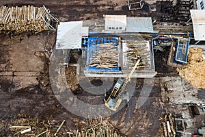 A loader loads logs at a wood processing factory from above from a drone