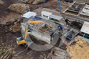 A loader loads logs at a wood processing factory from above from a drone