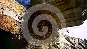 Loader machine unloading sand at eathmoving works at the construction site. Stock footage. Bottom view of the excavator