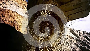 Loader machine unloading sand at eathmoving works at the construction site. Stock footage. Bottom view of the excavator