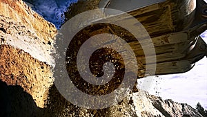 Loader machine unloading sand at eathmoving works at the construction site. Stock footage. Bottom view of the excavator