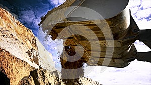 Loader machine unloading sand at eathmoving works at the construction site. Stock footage. Bottom view of the excavator