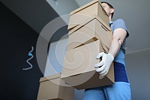 Loader man carries cardboard boxes in office
