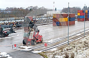 The loader stands on the site waiting for unloading or loading of cargo containers at the station.