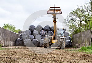 Loader tractor stacking round bales in a stack