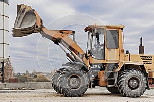 The loader is transporting sand or gravel in the front bucket. Heavy construction equipment at a construction site. Transportation