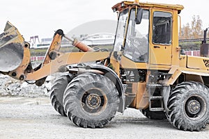 The loader is transporting sand or gravel in the front bucket. Heavy construction equipment at a construction site. Transportation