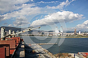 Loading cargo of cement clinker in bulk carrier by ships cranes in the port of Izmir, Turkey.