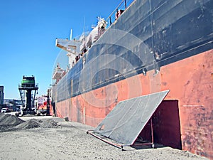 Loading cargo of cement clinker in bulk carrier by ships cranes in the port of Izmir, Turkey.