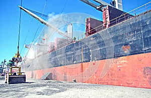 Loading cargo of cement clinker in bulk carrier by ships cranes in the port of Izmir, Turkey.