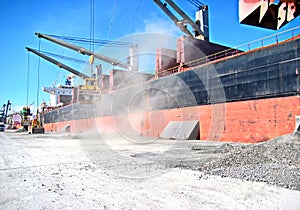 Loading cargo of cement clinker in bulk carrier by ships cranes in the port of Izmir, Turkey.