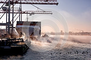 Loading cargo containers on the ship. The sea in the fog and the cargo complex