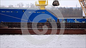 Loading coal from a barge to a transport ship with a crane on the Severnaya Dvina River.