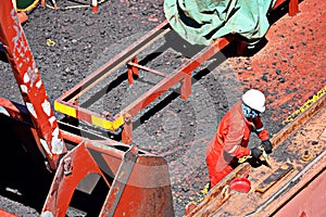 Loading coal from cargo barges onto a bulk carrier using ship cranes and grabs at the port of Muara Pantai, Indonesia. Close-up vi